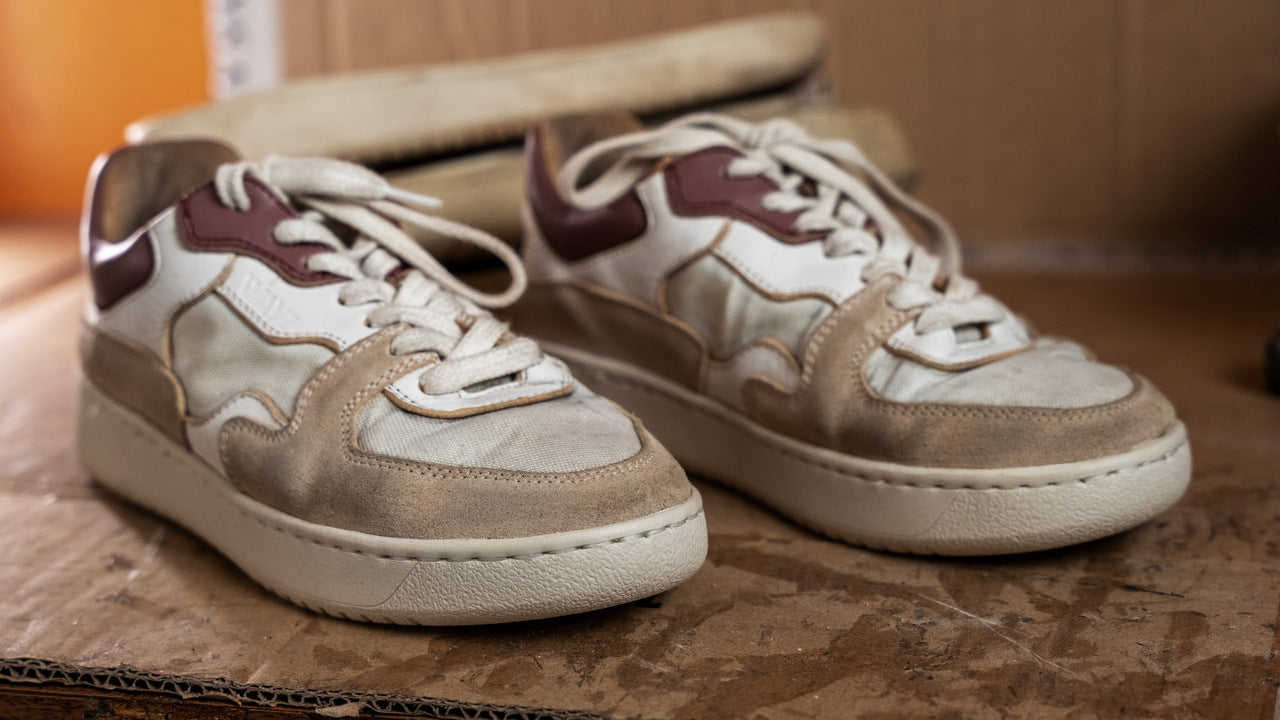 a worned out pair of the sonder white grey dry rose sneakers sitting on top of a sheet of cardboard