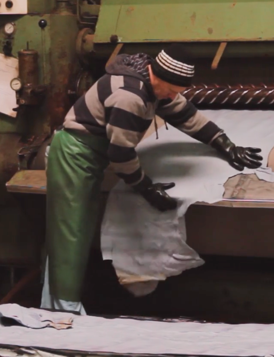 Wayz worker handling textiles in front of a machine