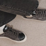 Wayz Grit Anthracite Black sneakers crossed legs stepping on carpet