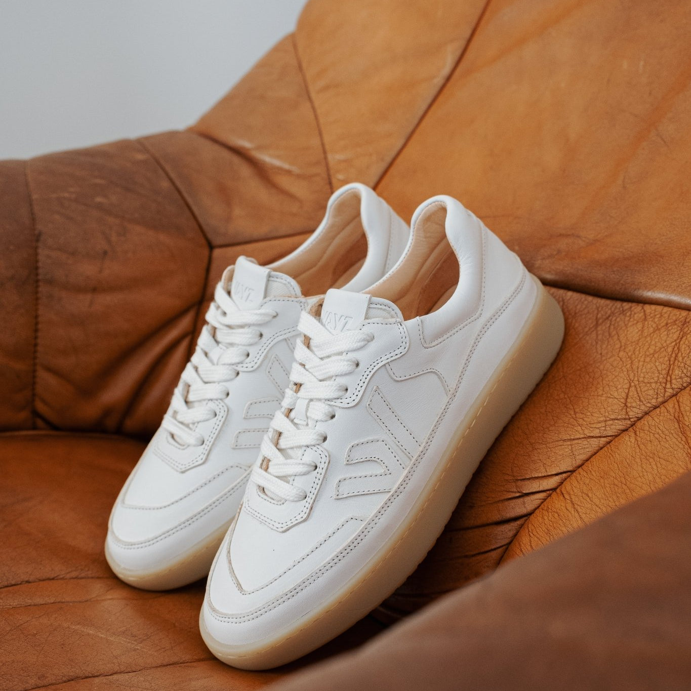 WAYZ Misfit White Gum sneakers on leather couch.